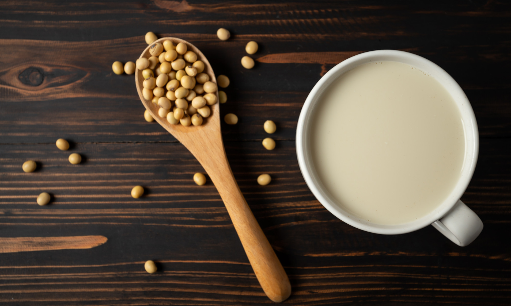 Soybeans and soy milk on a wooden table, representing natural nutrition, fermented foods, plant-based wellness, and the science behind nattokinase.