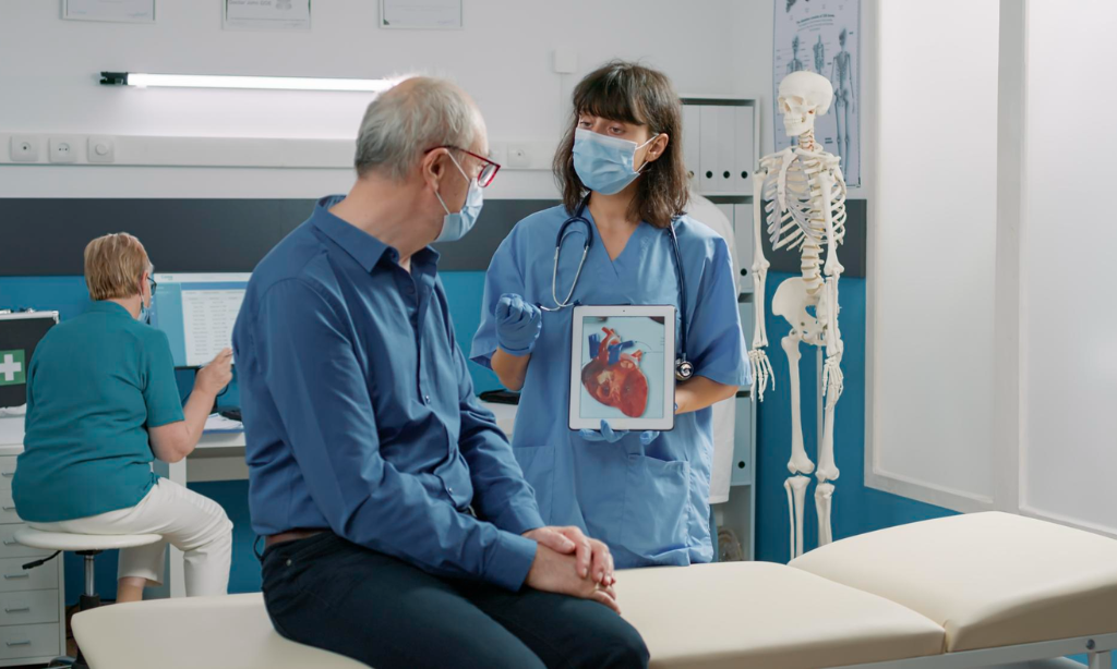 Doctor explaining heart anatomy on a tablet to an older patient in a medical clinic, illustrating circulation, fibrinolysis, and cardiovascular health support concepts.
