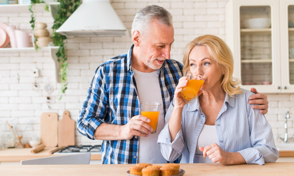 A middle-aged couple enjoying a healthy drink together in their kitchen, representing healthy lifestyle choices, healthy ageing, and everyday wellness habits.