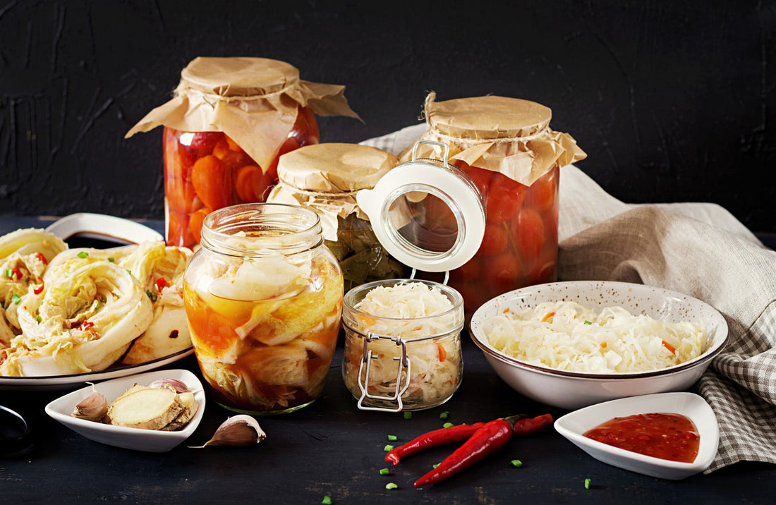 Assorted fermented foods including kimchi, sauerkraut, and pickled vegetables displayed in glass jars, highlighting gut health and microbiome-friendly nutrition.