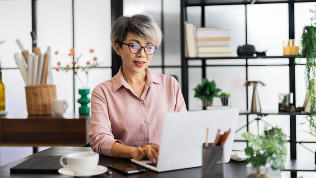 Woman sitting at a desk, typing on a laptop