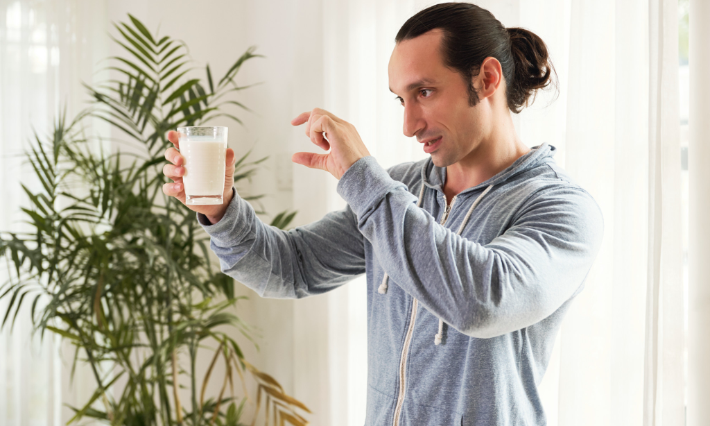 Man taking a daily supplement with a glass of milk at home, representing a consistent morning supplement routine and healthy lifestyle habits.