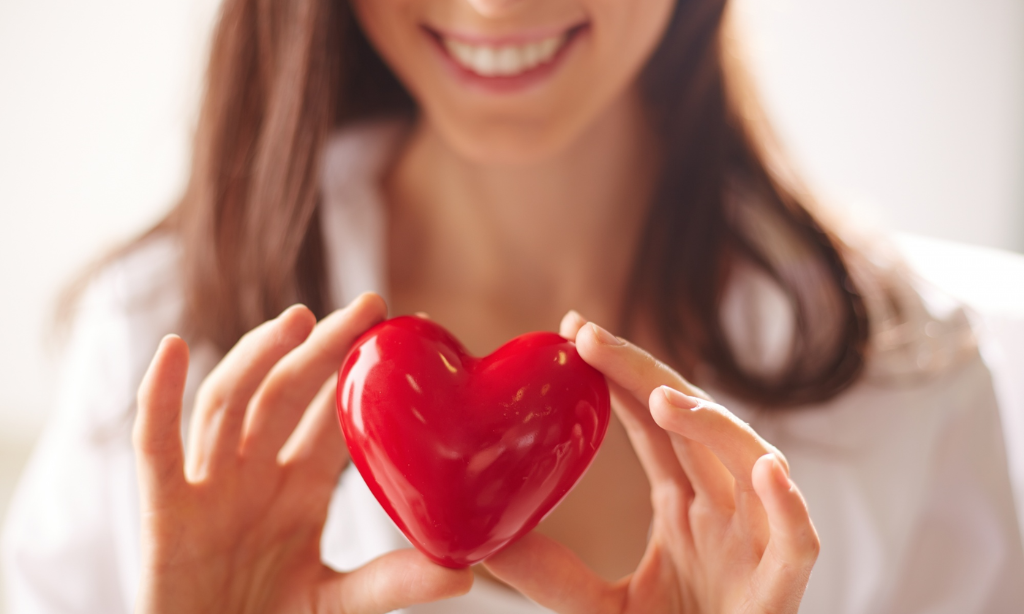 Woman holding red heart symbol representing heart health and wellness after 30