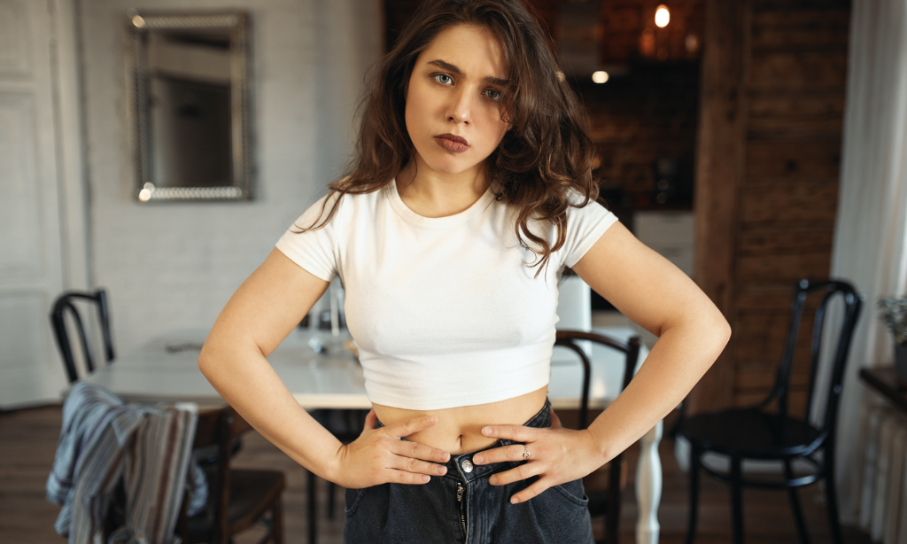 Woman holding her stomach indoors, illustrating bloating, digestive discomfort, and common gut health issues