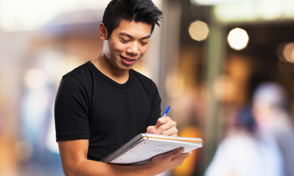 Young man writing in a notebook, focused and engaged in a learning task.